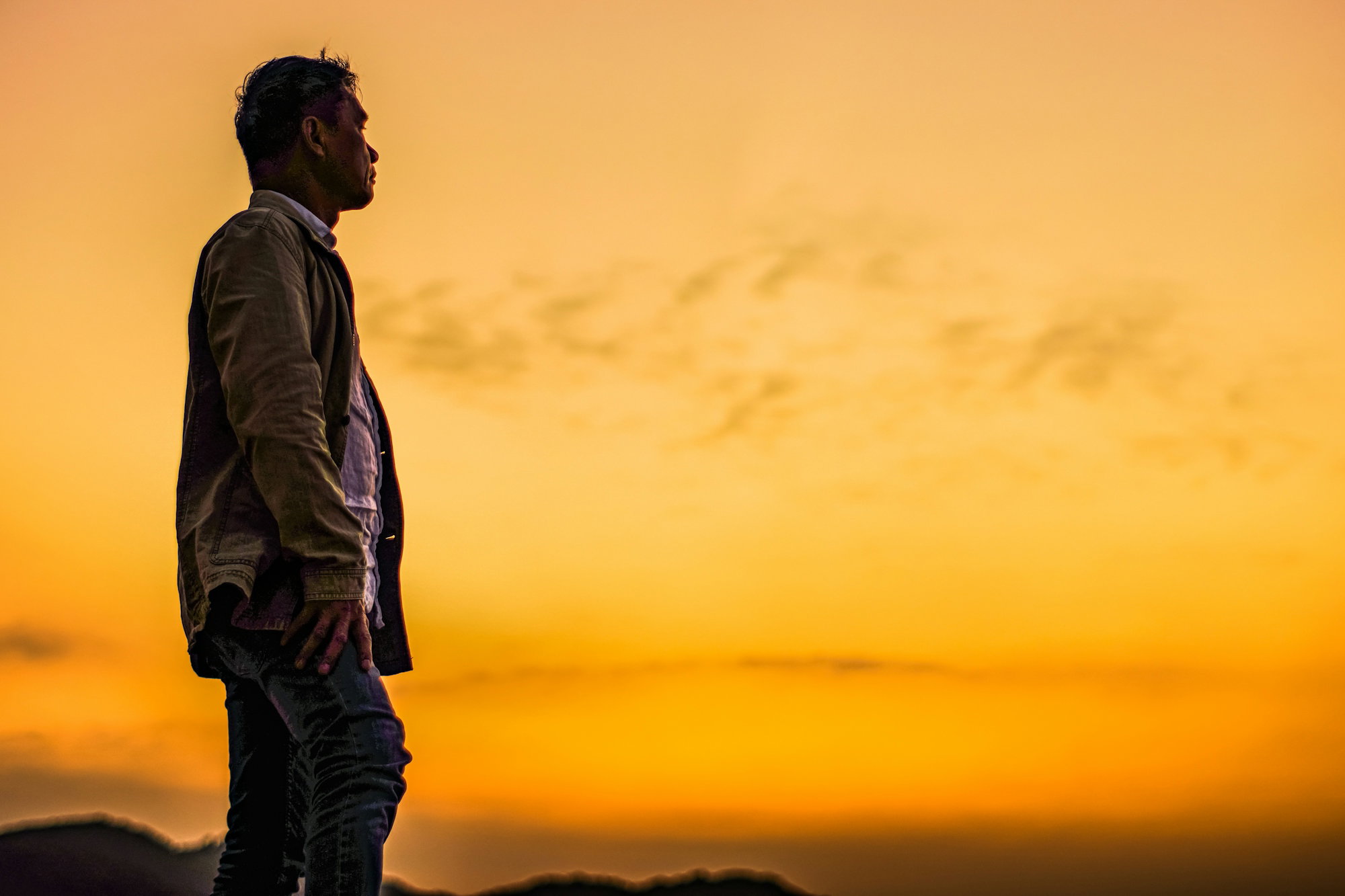 a man standing on top of a hill at sunset